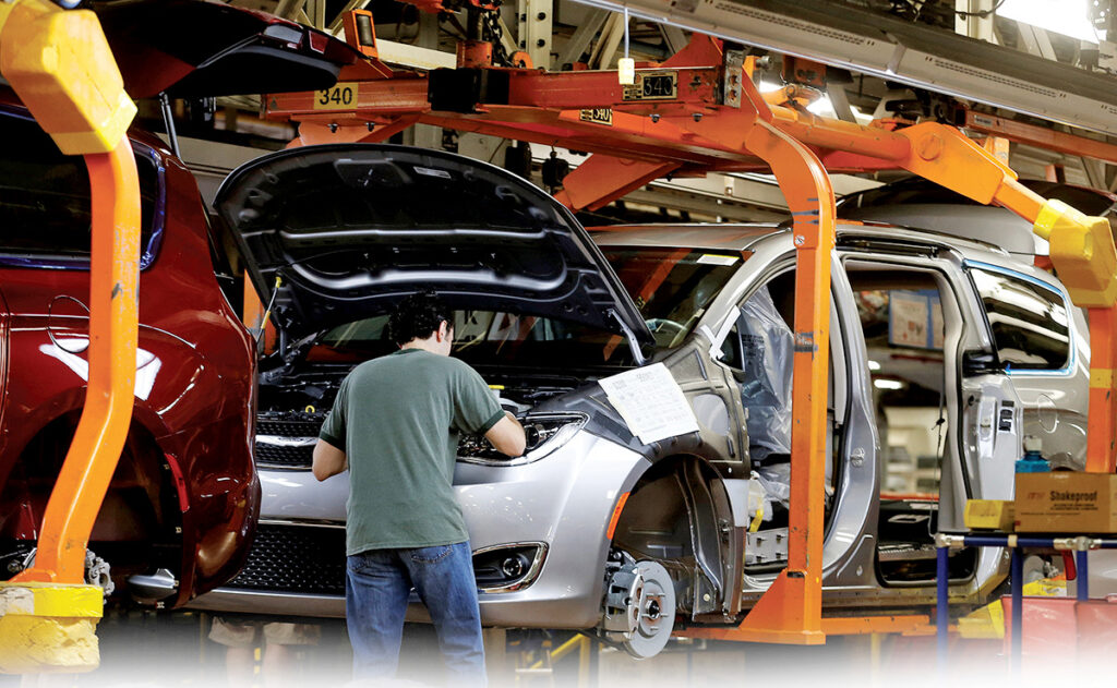 A factory worker assembles a vehicle.