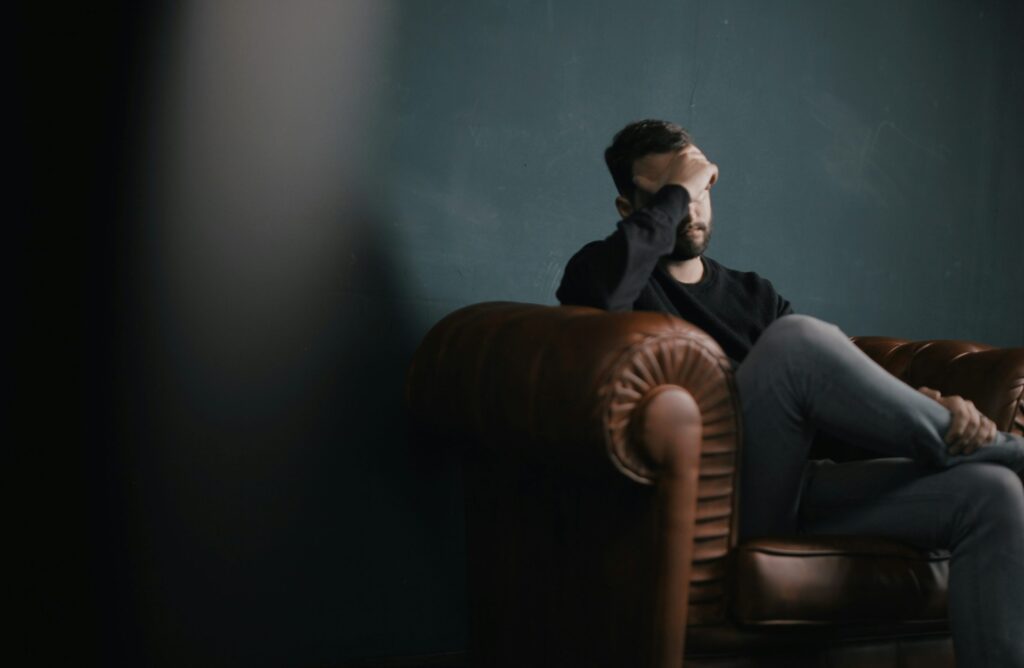 A man sitting down in a chair looking stressed out
